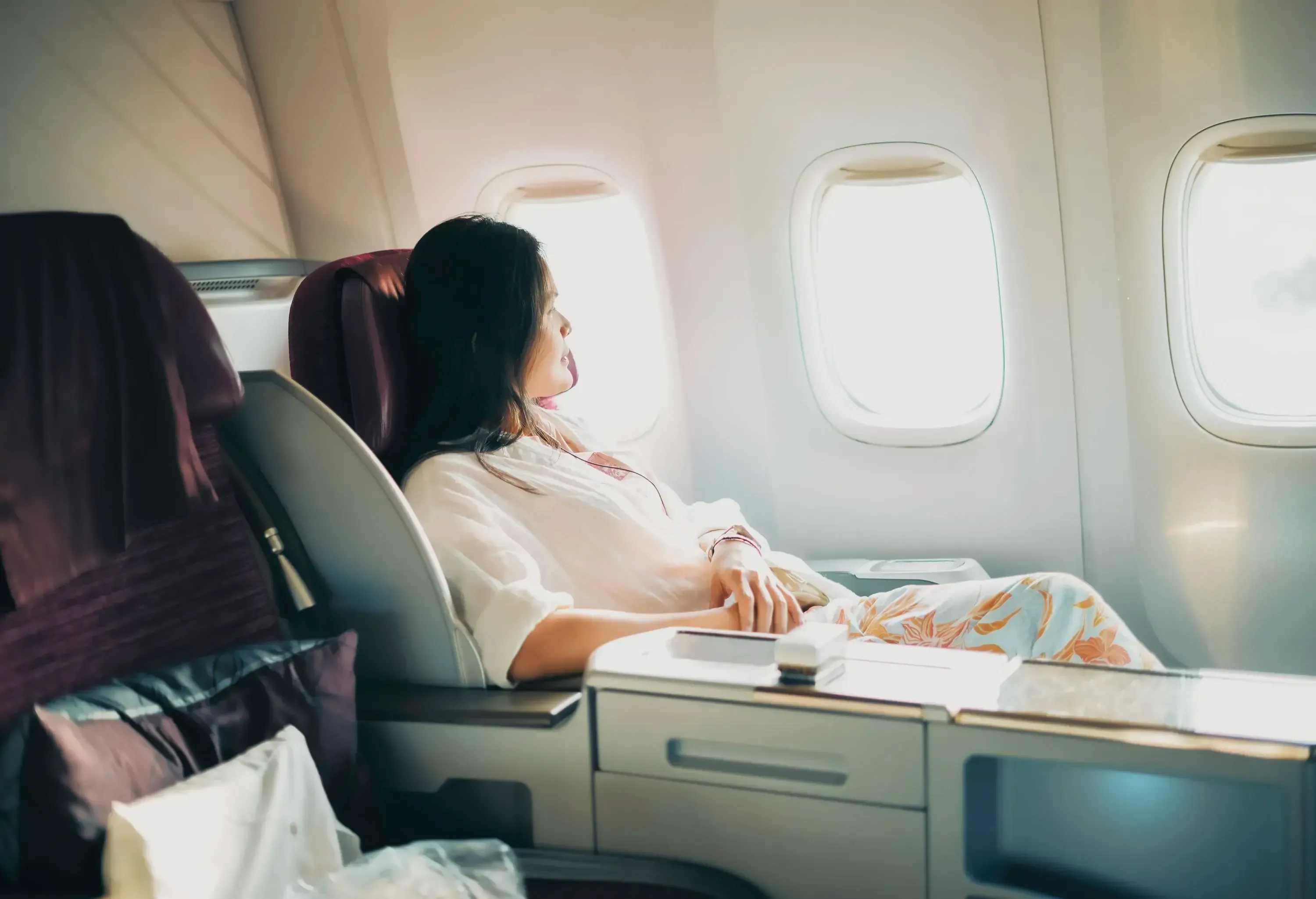 A relaxed business class passenger is looking out of the window of a passenger aircraft.