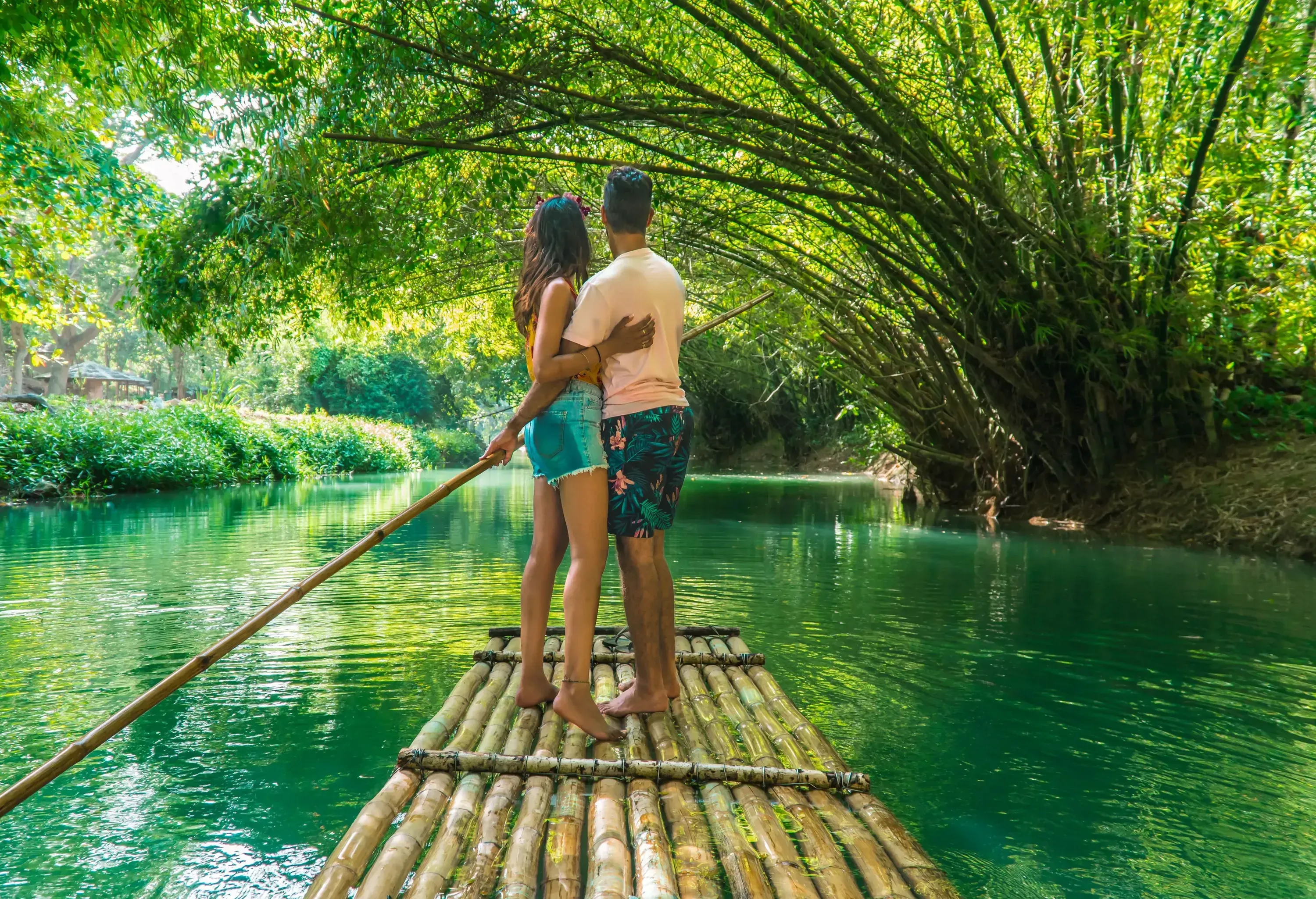 A couple hug while standing on a bamboo raft while cruising a river.