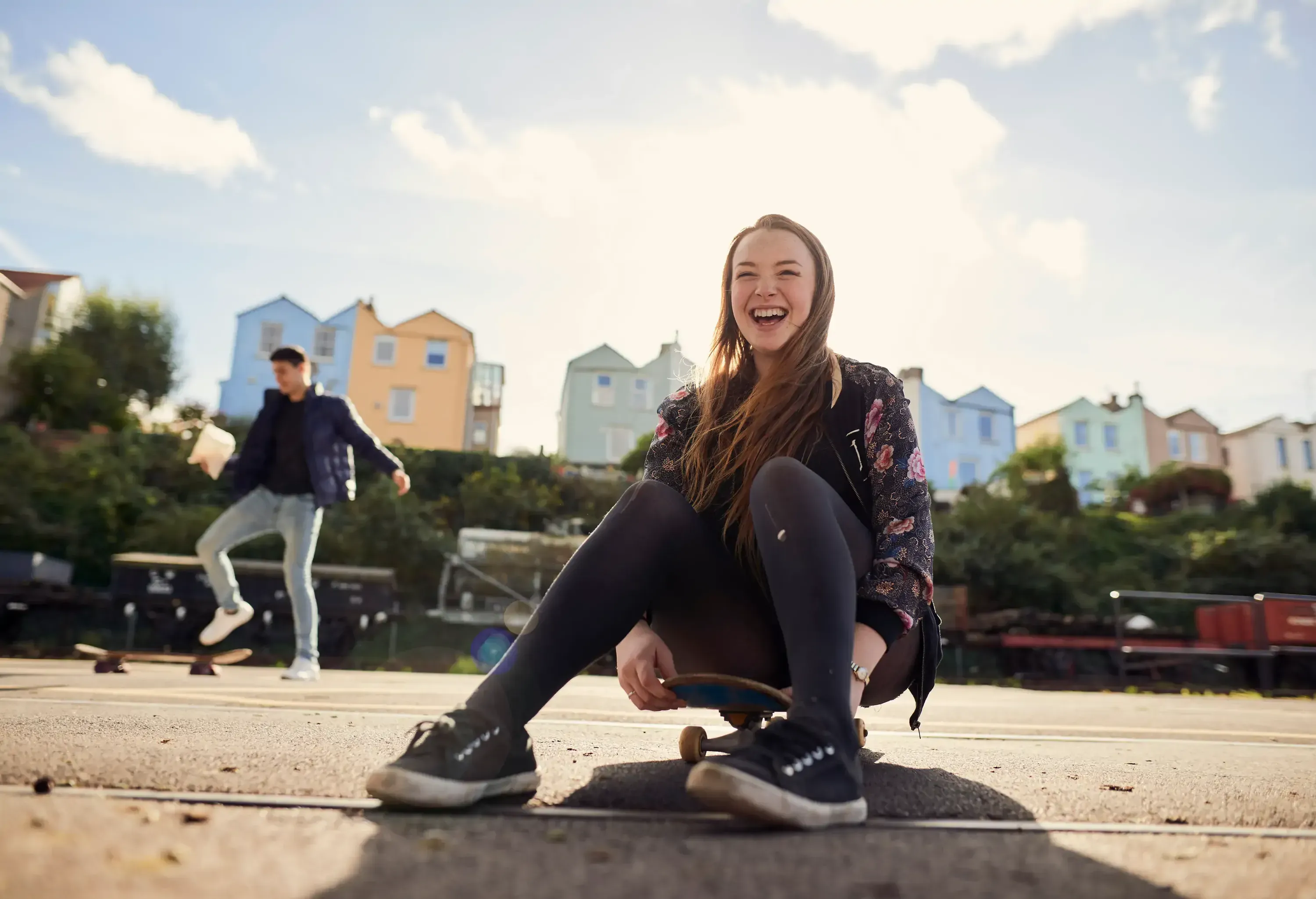 Girl laughing while sitting on a skateboard