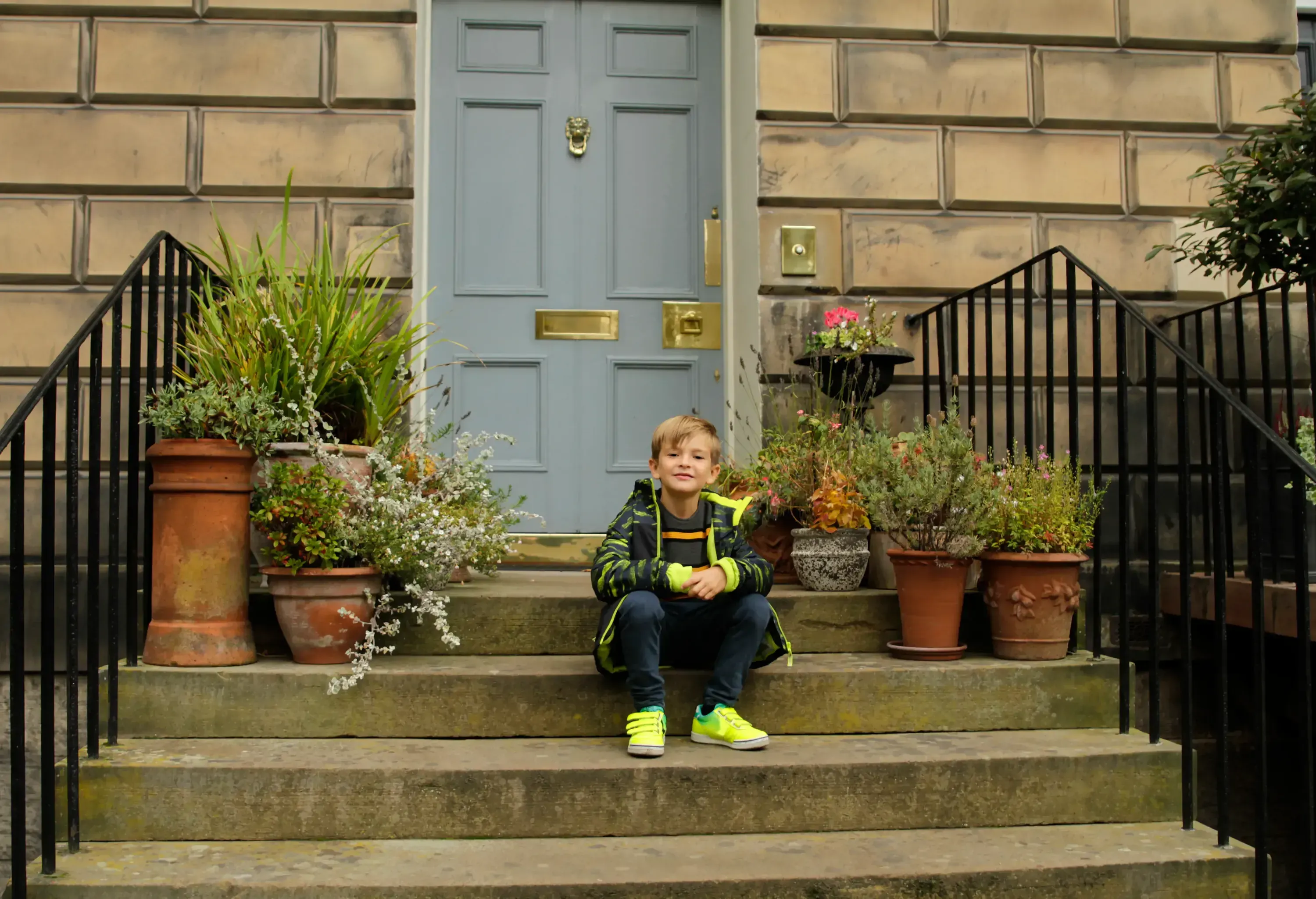 Little boy resting in front of house