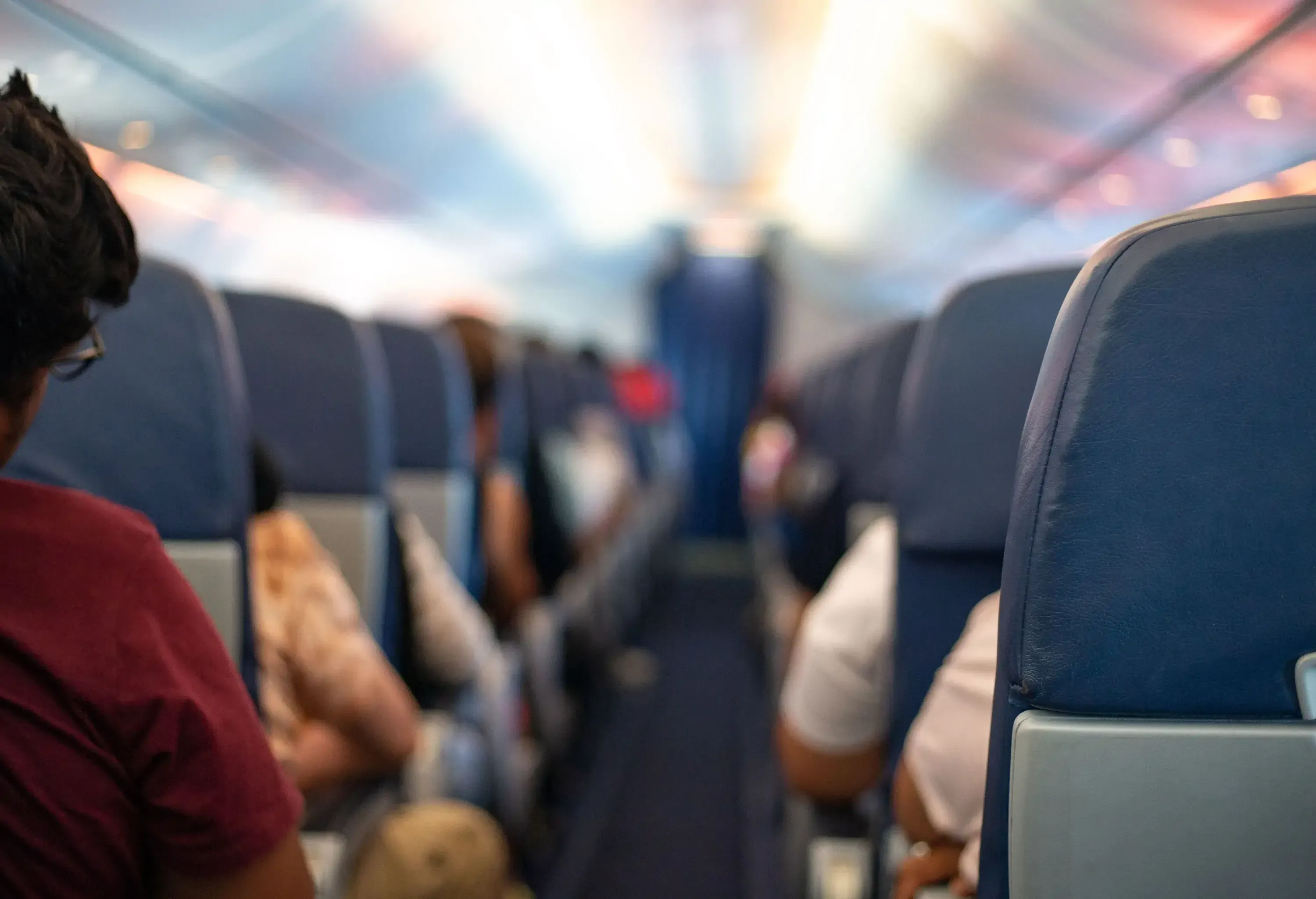 An empty airplane aisle with passengers comfortably settled in their seats.