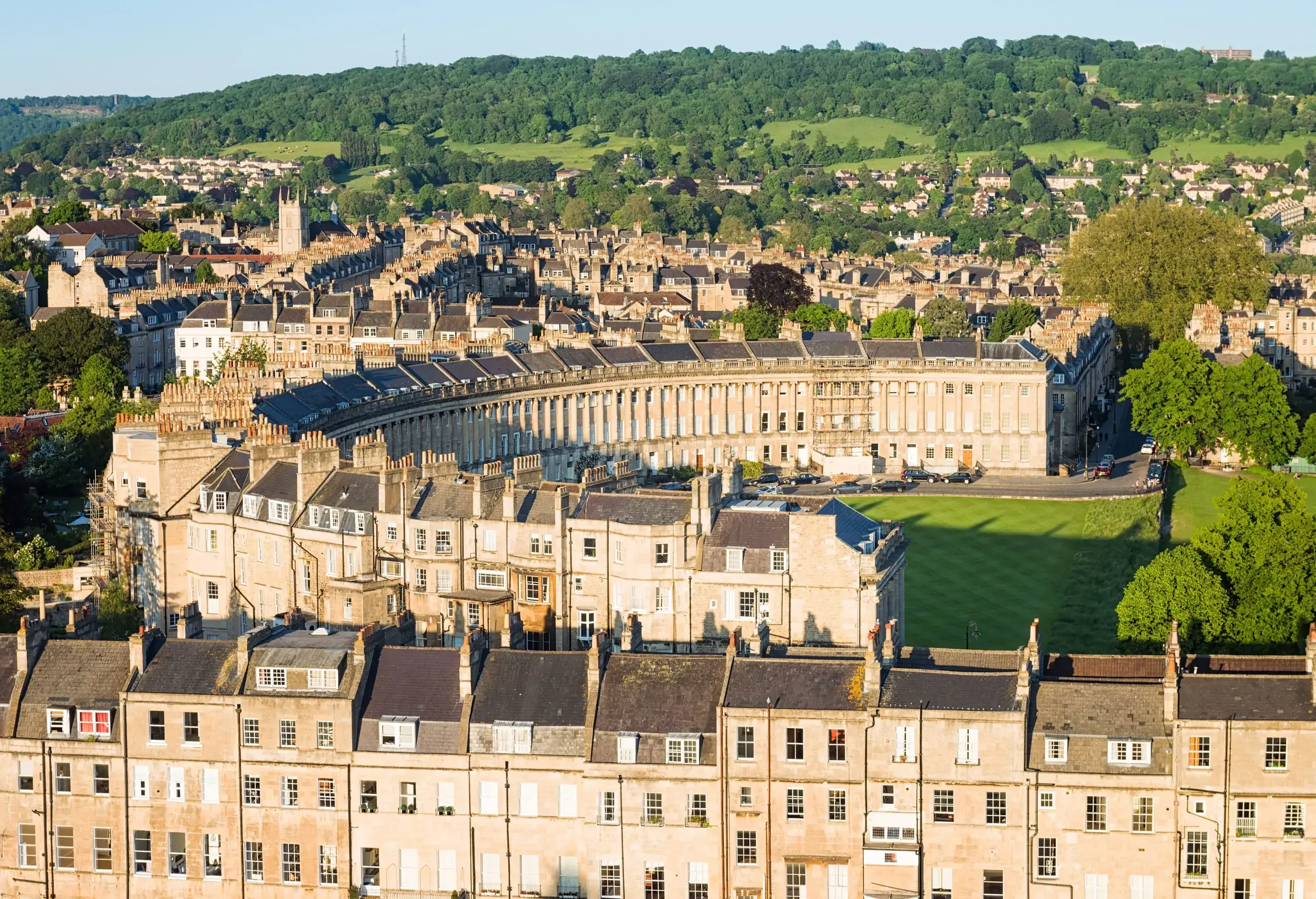 Aerial view of a town with rows of classic stone houses and buildings on a lush hill.