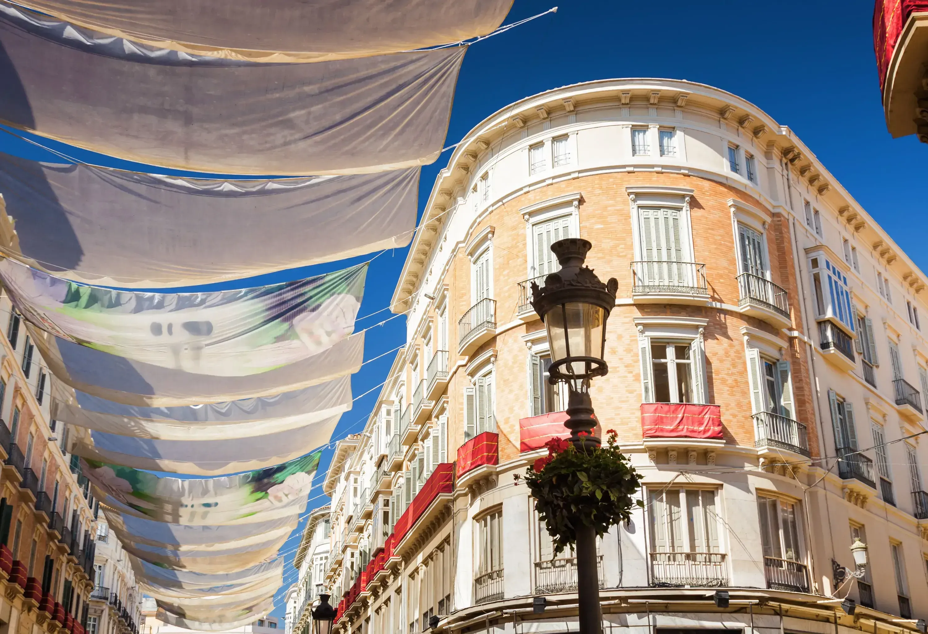 A canopy of white fabrics hanging above a street lined with stunning old buildings.