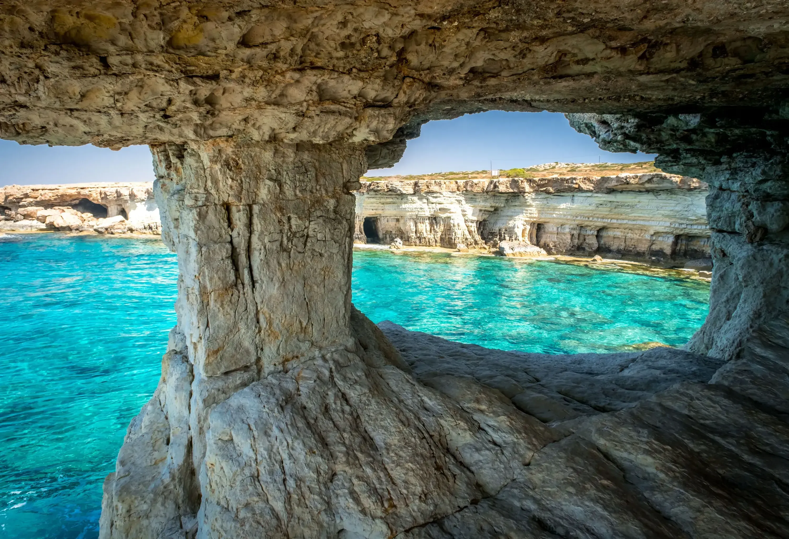 A seaside cave with entrance overlooking the crystal-clear waters.