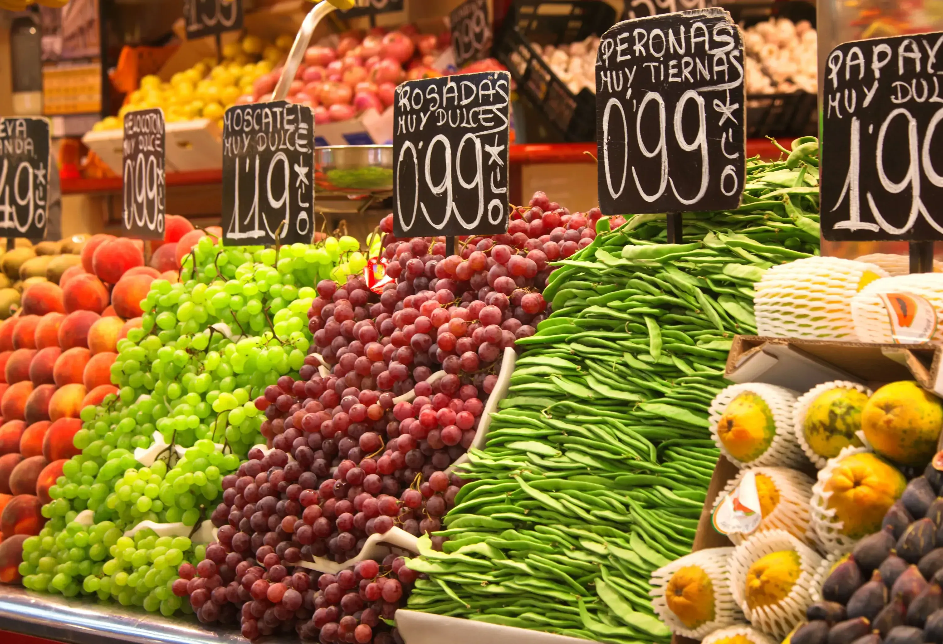 A colourful display of fruits and vegetables with its labels and price.