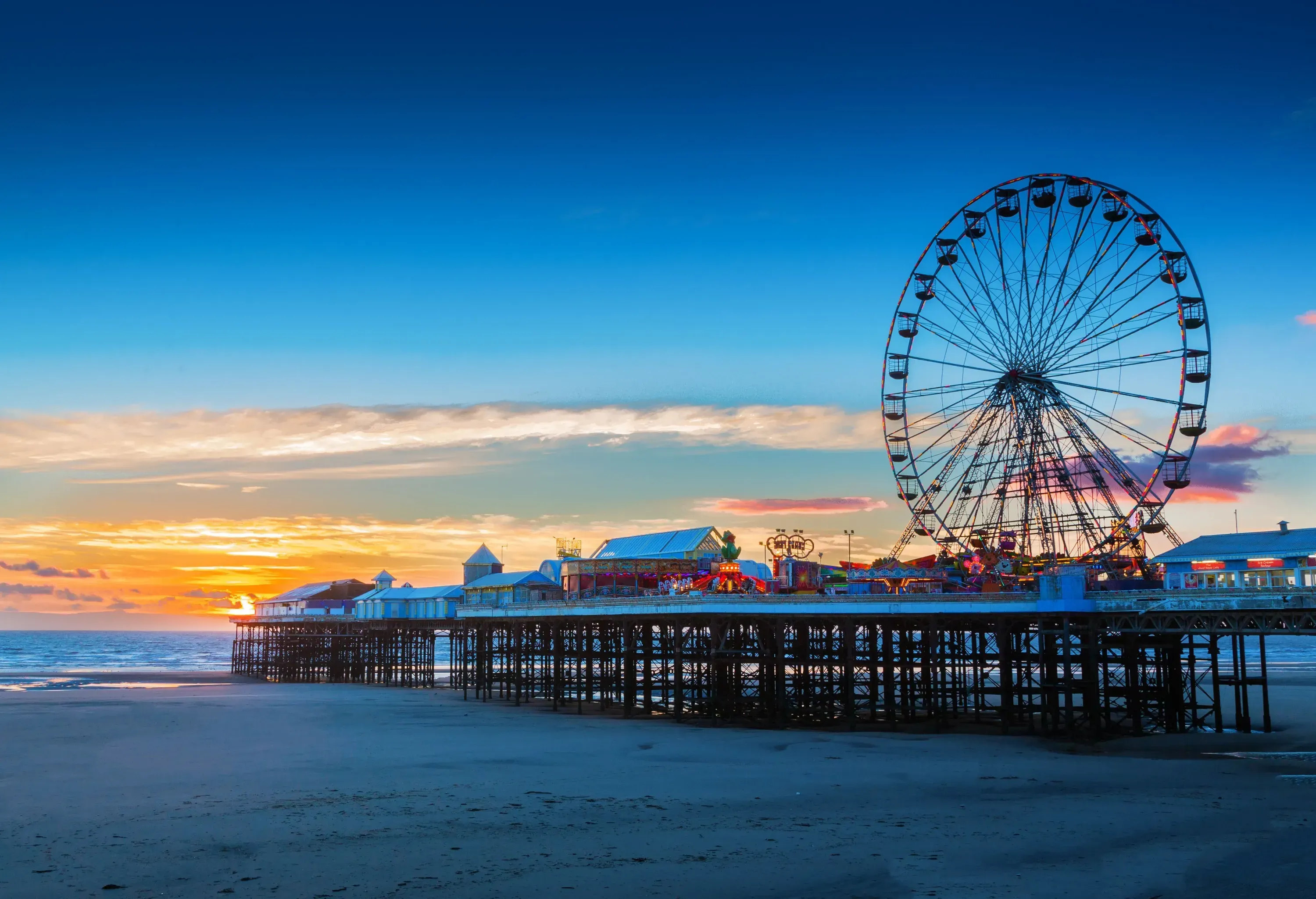 A compact amusement park with a big Ferris wheel on the pier.